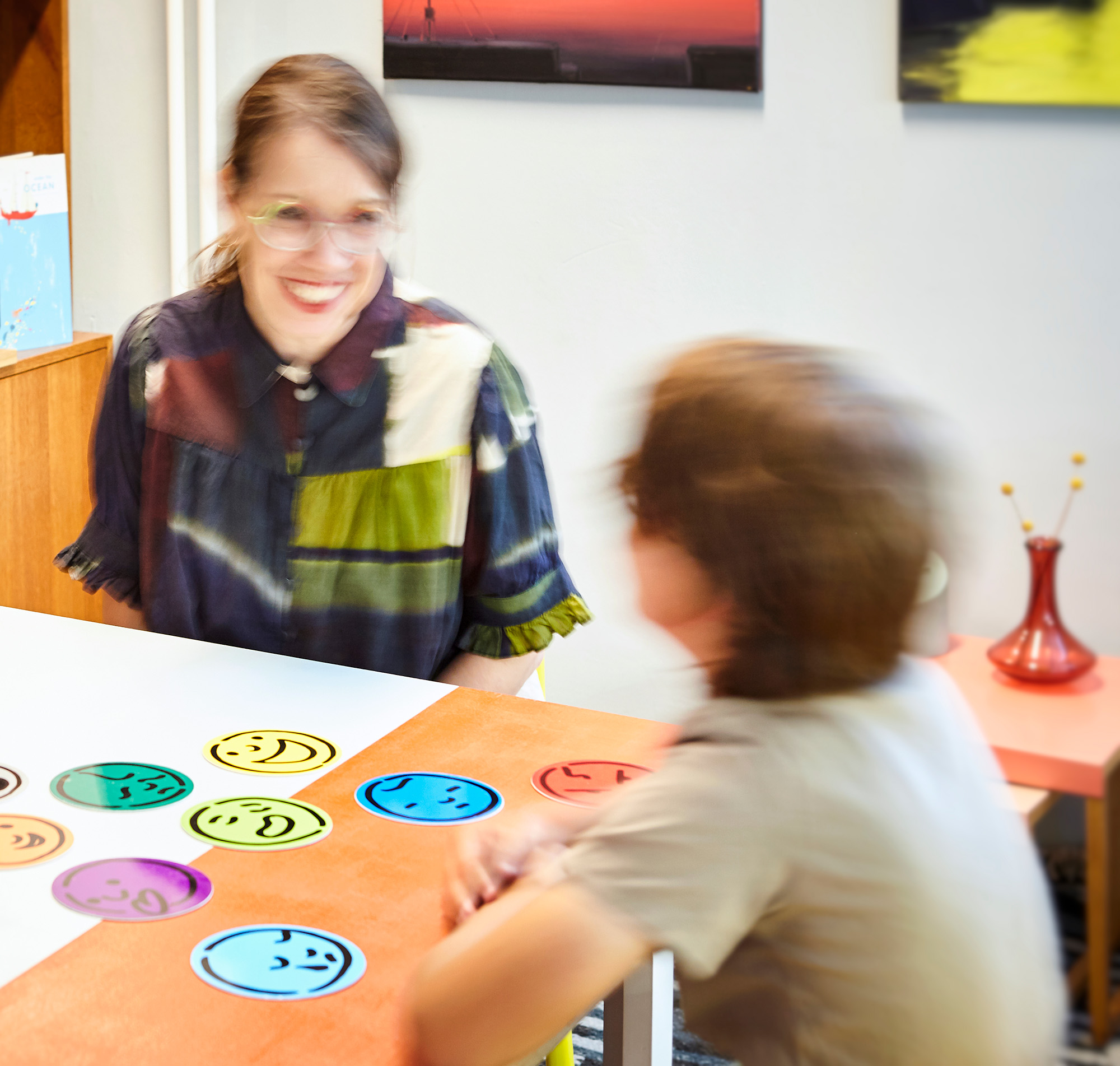 praxis-familie-und-recht_start Die Familienpsychologin unterhält sich freundlich mit einem Kind in ihrer Praxis.